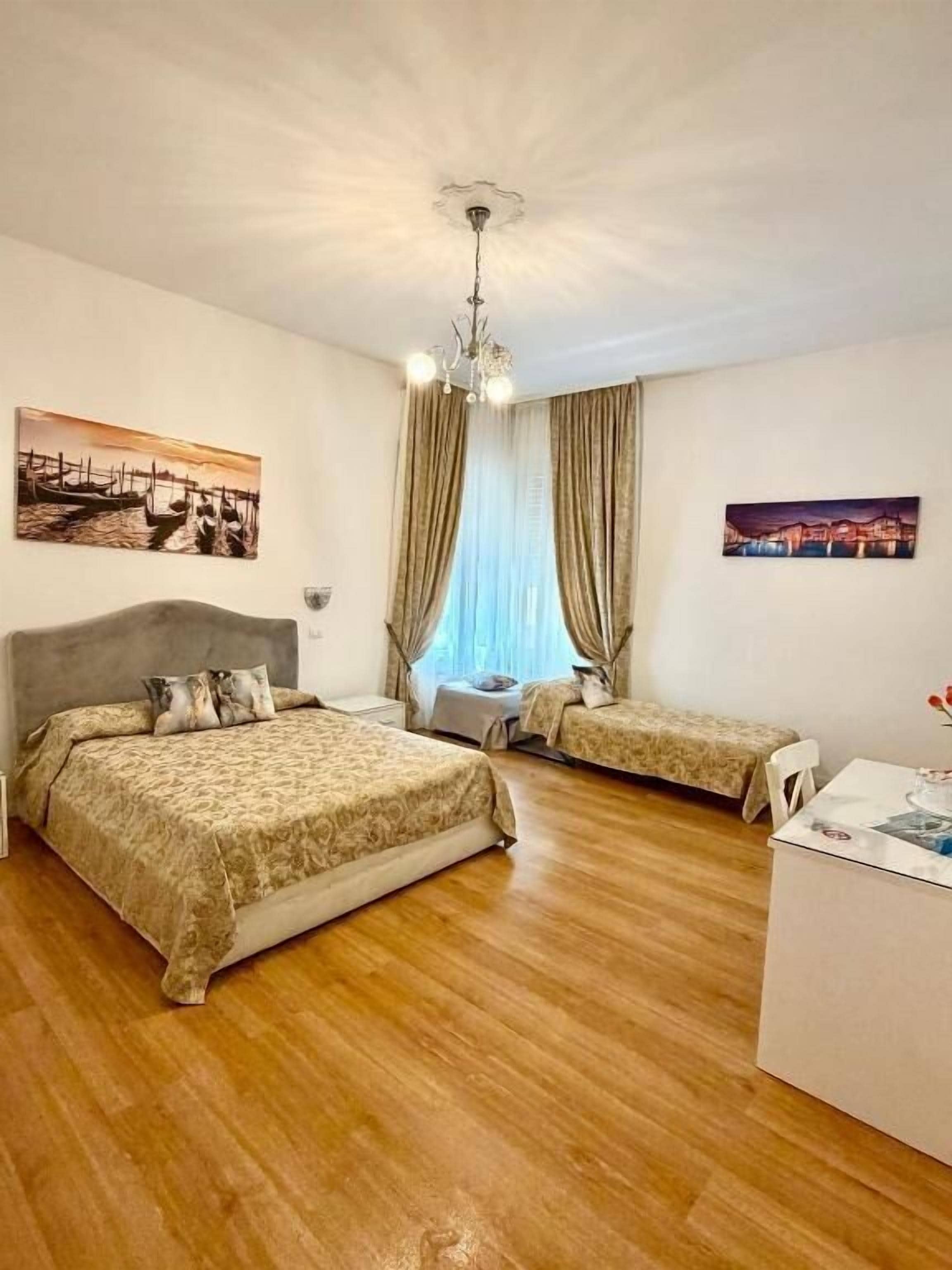 A hotel room with a large bed, a smaller bed, a desk, and a chair.