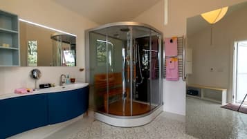 Een moderne badkamer met een douchecabine van glas, een wastafel met spiegel en een vloer met een patroon.