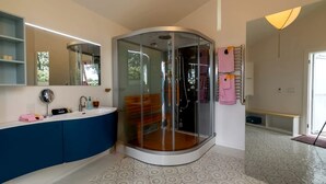 A modern bathroom with a glass-enclosed shower, a vanity with a mirror, and a patterned floor. - Romantic Luxury Yurt with Private Beach & Steam Shower near Friendship, Maine (Friendship)