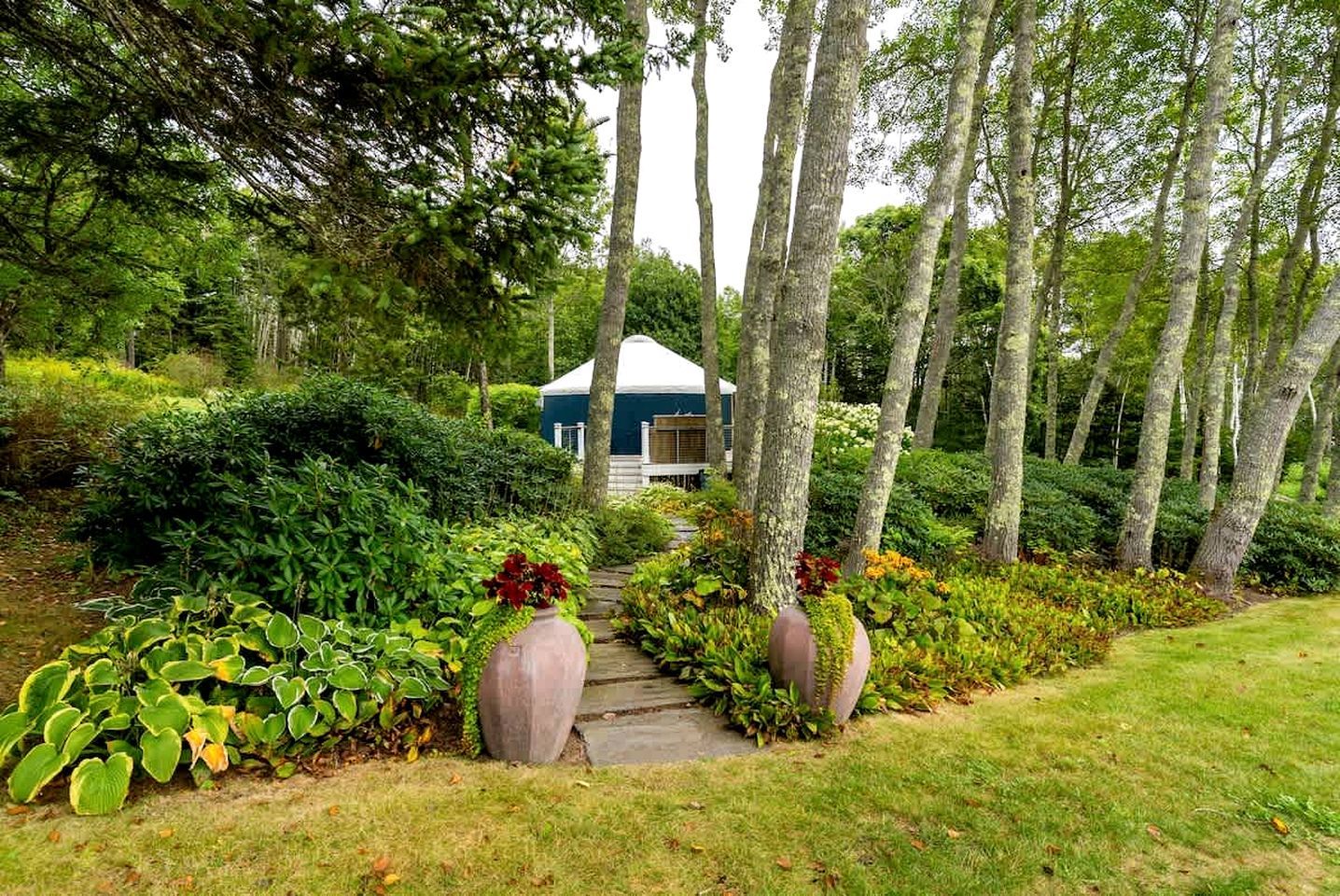 A pathway leading to a building surrounded by lush greenery and trees.