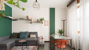 A modern living room with a sectional sofa, a glass dining table, and a green accent wall. - A modern and welcoming 55-square-meter apartment, ideal for up to 4 guests, located on the first floor of a building with an elevator. The property is situated in Brenta, a quiet residential area a short distance from Porta Romana and the new Scalo Roman (Milan)