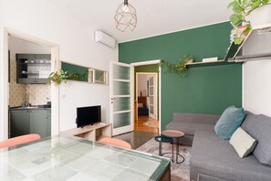A compact living space with a dining table, a sofa, a TV, and a kitchen area. - A modern and welcoming 55-square-meter apartment, ideal for up to 4 guests, located on the first floor of a building with an elevator. The property is situated in Brenta, a quiet residential area a short distance from Porta Romana and the new Scalo Roman (Milan)