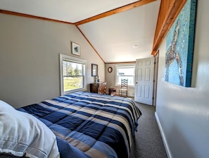 A bedroom with a large bed, a dresser, a chair, and a door leading to another room. - Rustic Waterfront Beach House with Private Beach, Fire Pit & Dock, Near Bar Harbor in Hancock, Maine (Hancock)