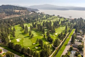 A golf course with a water body in the background, surrounded by dense forests and residential areas. - Cozy Studio Near Downtown Coeur d'Alene, The Flats (Coeur d'Alene)