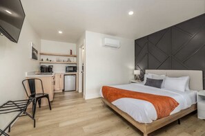 A compact hotel room with a bed, bedside table, and a small kitchenette. - Cozy Studio Near Downtown Coeur d'Alene, The Flats (Coeur d'Alene)