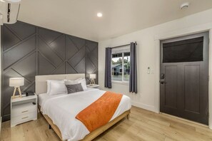 A modern bedroom with a bed, nightstands, a window, and a door. - Cozy Studio Near Downtown Coeur d'Alene, The Flats (Coeur d'Alene)