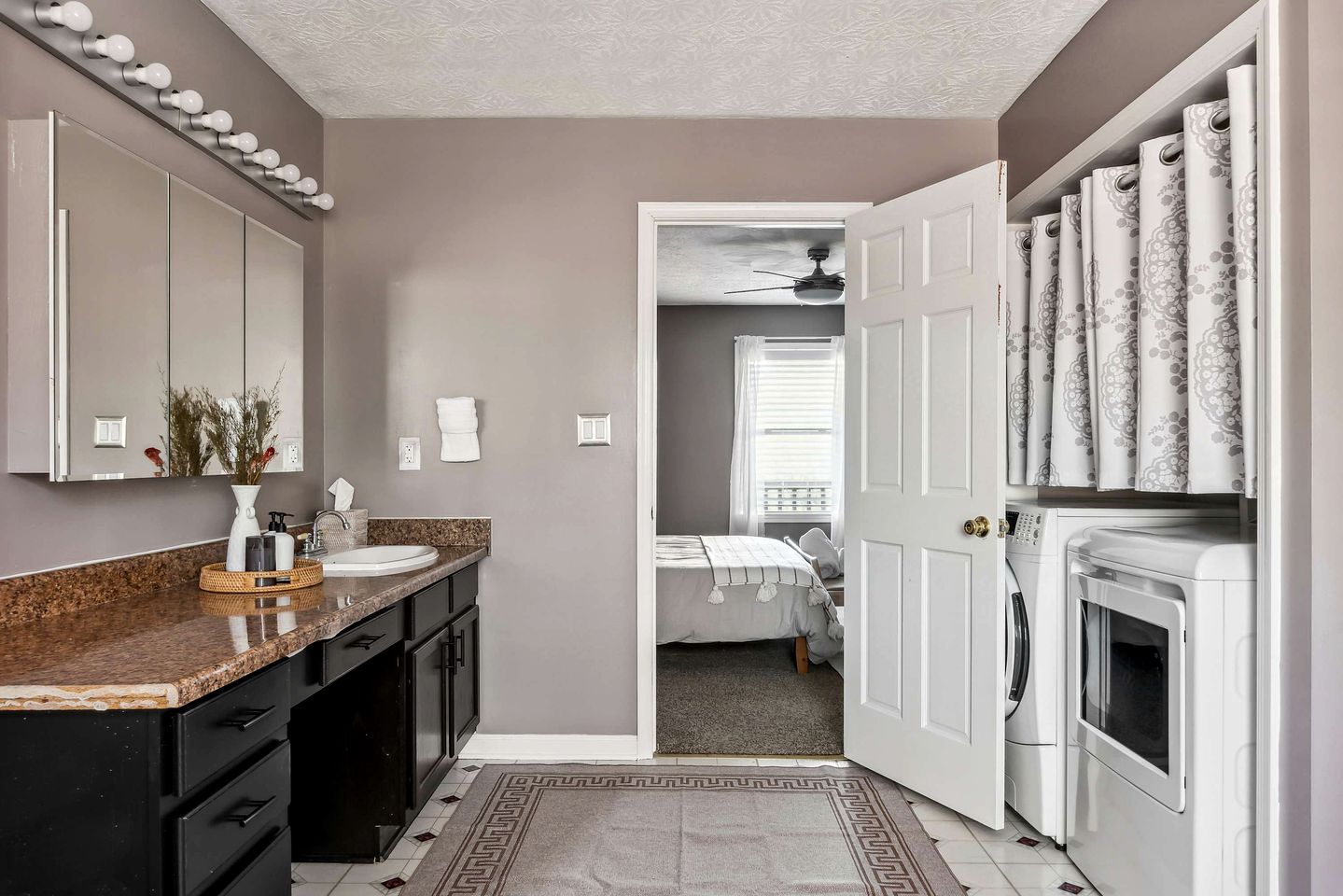 A modern bathroom with a vanity, sink, mirror, and towel rack.