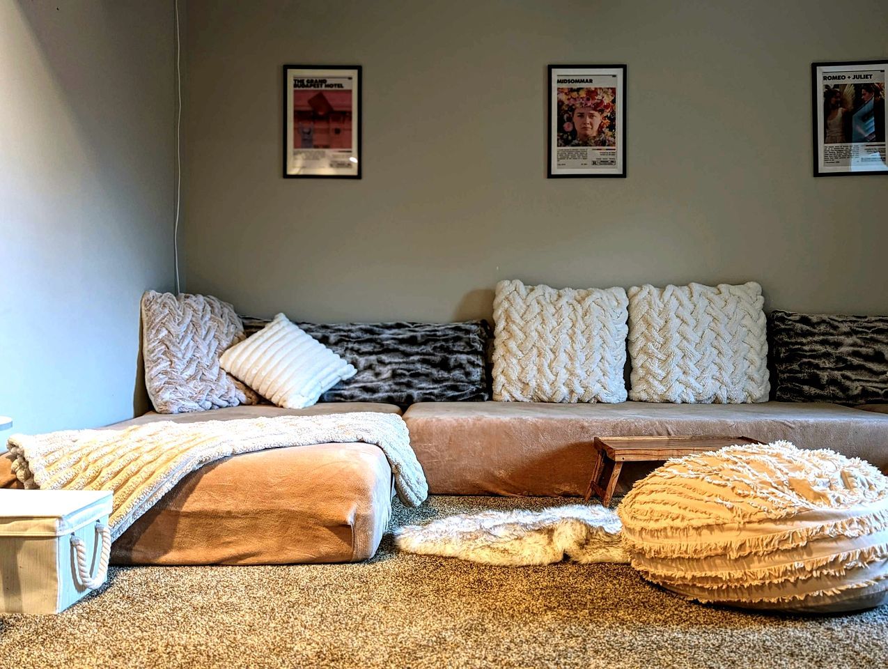 Een gezellige kamer met een bank, kussens, een plaid en een klein houten tafeltje.