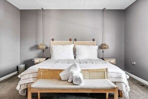 A bedroom with a bed, two bedside tables, a bench, and a hanging lamp. - Secluded Modern-Rustic Cabin with Hot Tub & Sunrise Old Rag Views near Shenandoah National Park, Luray VA (Luray)