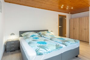 A bedroom with a bed, nightstands, a wardrobe, and a ceiling with recessed lighting.