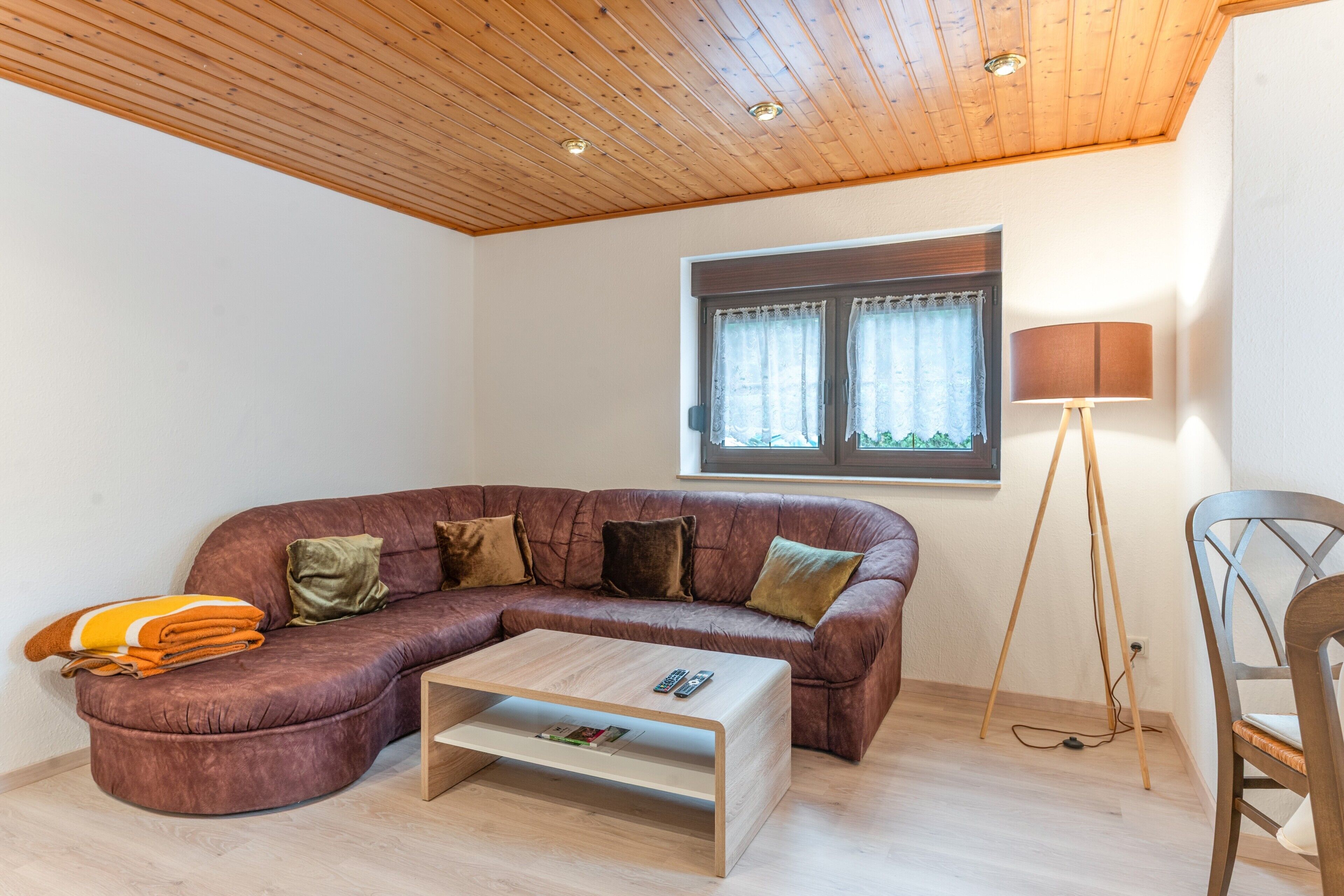 A living room with a curved sofa, a coffee table, a lamp, and a window with curtains.