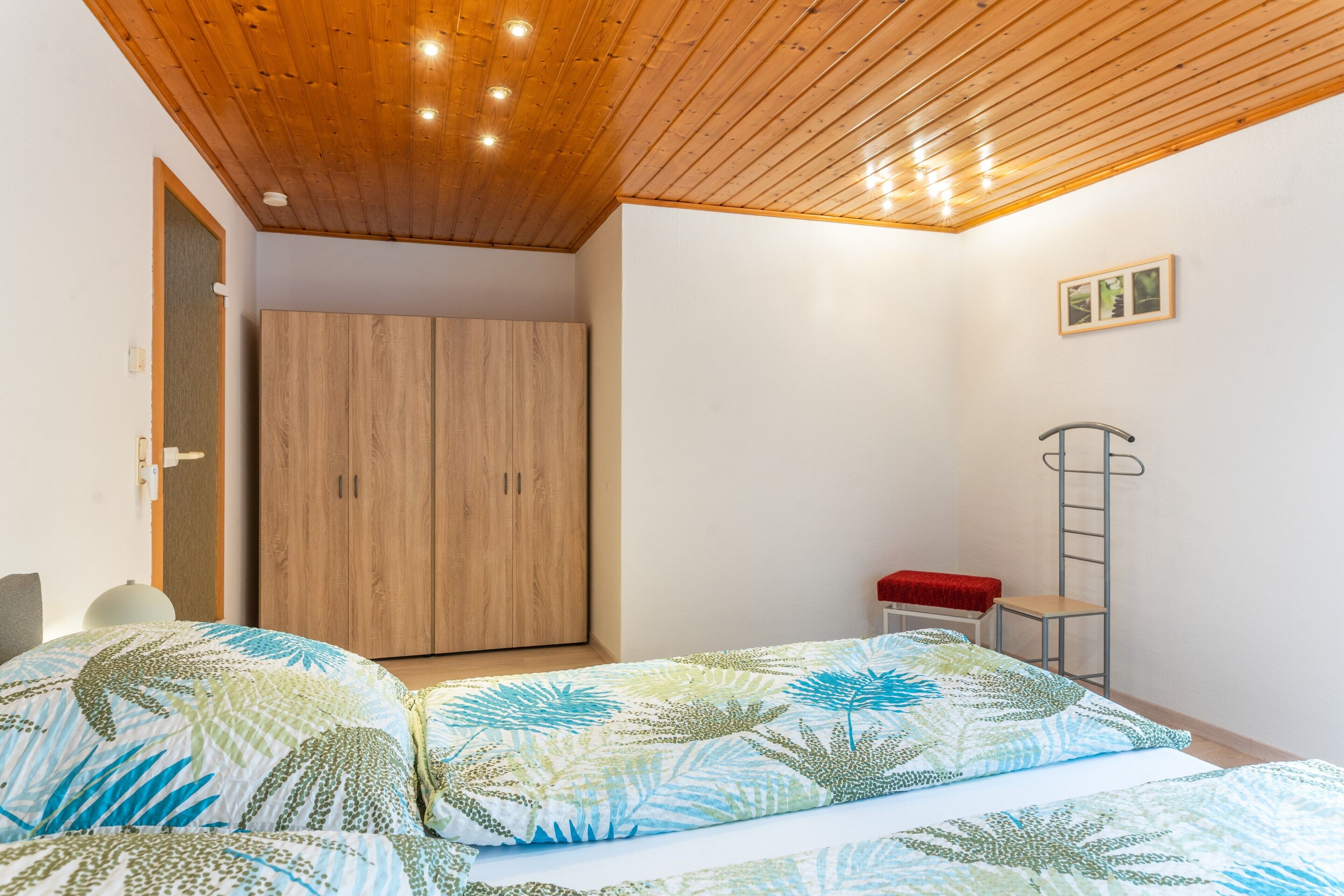 Ein Schlafzimmer mit zwei Betten, einem Kleiderschrank, einer Leiter und einem kleinen Tisch.
