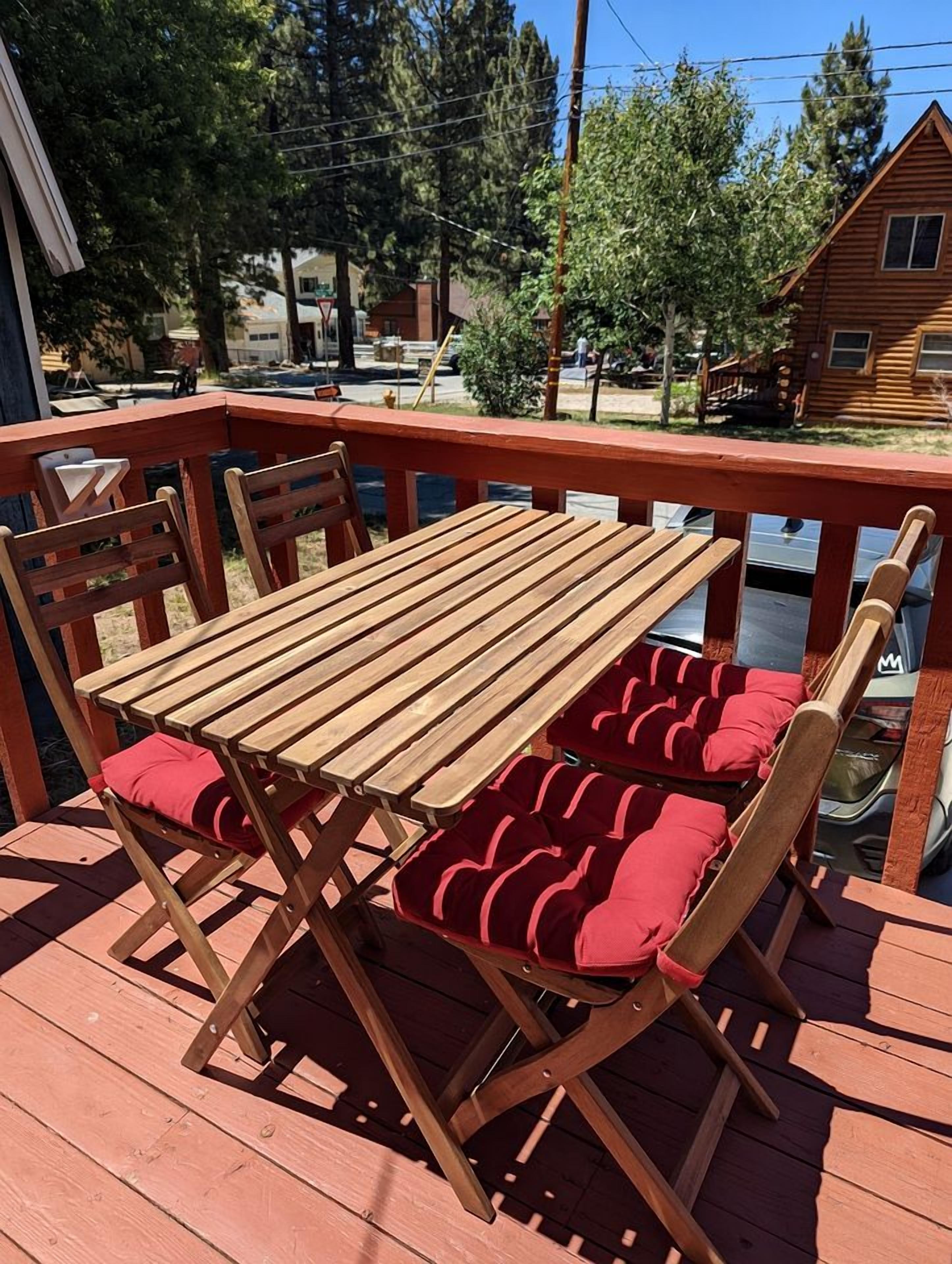 A wooden deck with a table and chairs, surrounded by a railing.
