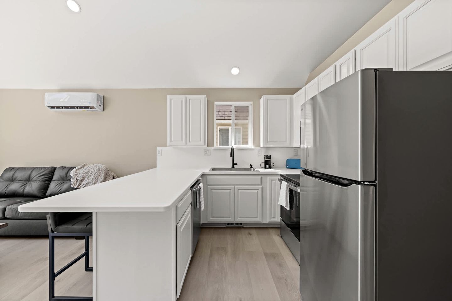 A modern kitchen with white cabinetry, a stainless steel refrigerator, and a built-in oven.