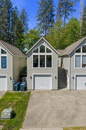 Une rangée de maisons de plain-pied avec des garages attenants, entourées d’arbres.