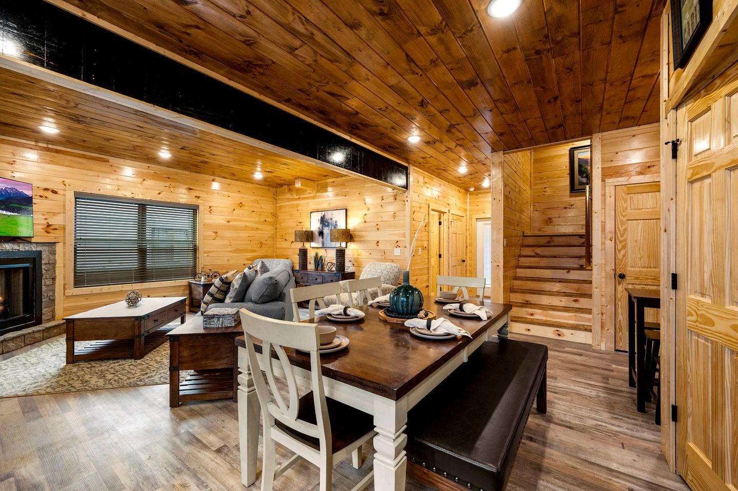 A log cabin interior with a dining area, seating, and a fireplace.