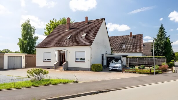 En tvåvånings bostadsbyggnad med ett garage, en uppfart och en liten trädgårdsyta.