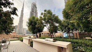 Terraza en la azotea con mobiliario exterior, una parrilla y vistas del Burj Khalifa.
