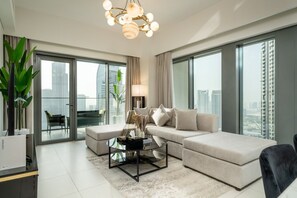 A modern living room with a sofa, a coffee table, and a balcony with a city view. - Gogoto9 Spacious 3BR Burj Khalifa view High Floor (Dubai)