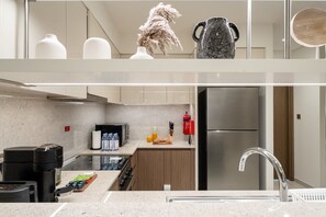 A modern kitchen with a stainless steel refrigerator, a coffee machine, and a microwave. - Gogoto9 Spacious 3BR Burj Khalifa view High Floor (Dubai)