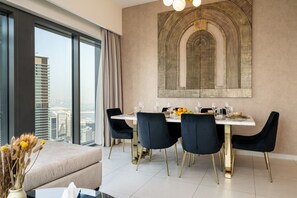 A dining area with a table set for four, a large window with curtains, and a city view. - Gogoto9 Spacious 3BR Burj Khalifa view High Floor (Dubai)