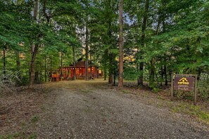 Eine Holzhütte, umgeben von Bäumen, mit einem Schotterweg, der dorthin führt.