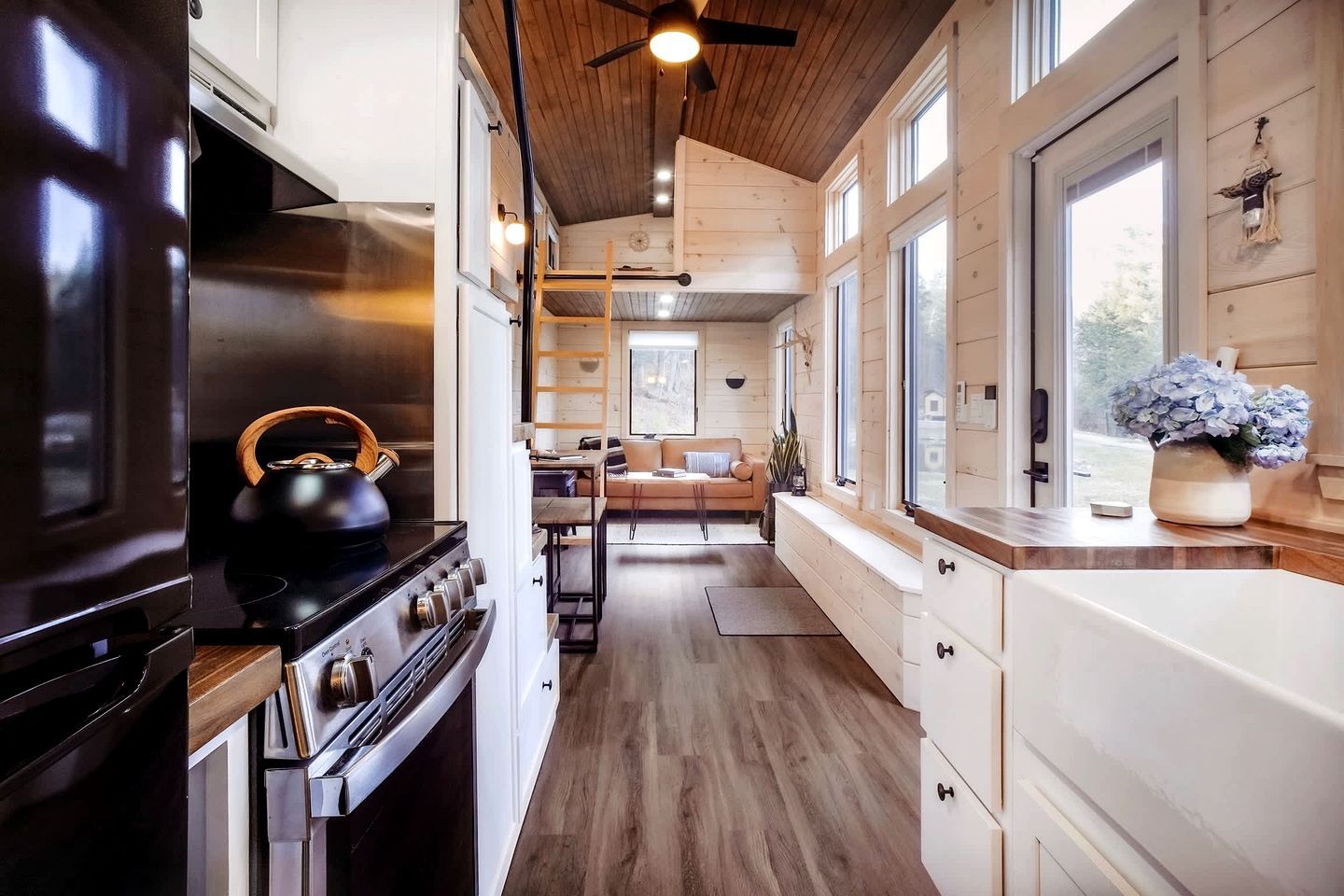 Une cuisine moderne avec des meubles en bois, une cuisinière et un coin repas comprenant un canapé et une table.