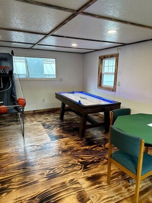 A room with a pool table, a basketball hoop, and a window. - Enchanting Historic Cabin Retreat near Mount Rushmore in South Dakota (Keystone)