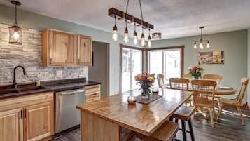 A kitchen with wooden cabinets, a central island, and pendant lighting.