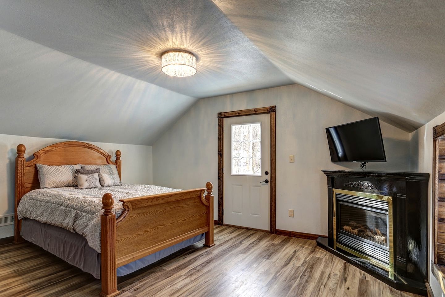 A bedroom with a wooden bed, a television, and a fireplace.