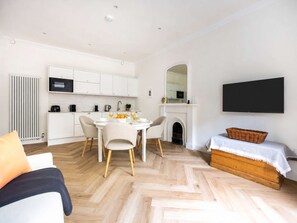 A modern living room with a fireplace, a dining area, and a kitchen with white cabinetry and appliances. - Spacious 1BR in Heart of New Town & Royal Crescent (Edinburgh)