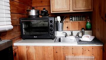 A compact kitchen with a built-in oven, a sink, and wooden cabinets.
