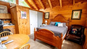 A wooden cabin with a bed, a dining table, and a chair. - Cozy Log Cabin near Cumberland Lake State Park, Perfect for an Outdoor Adventure (Columbia)