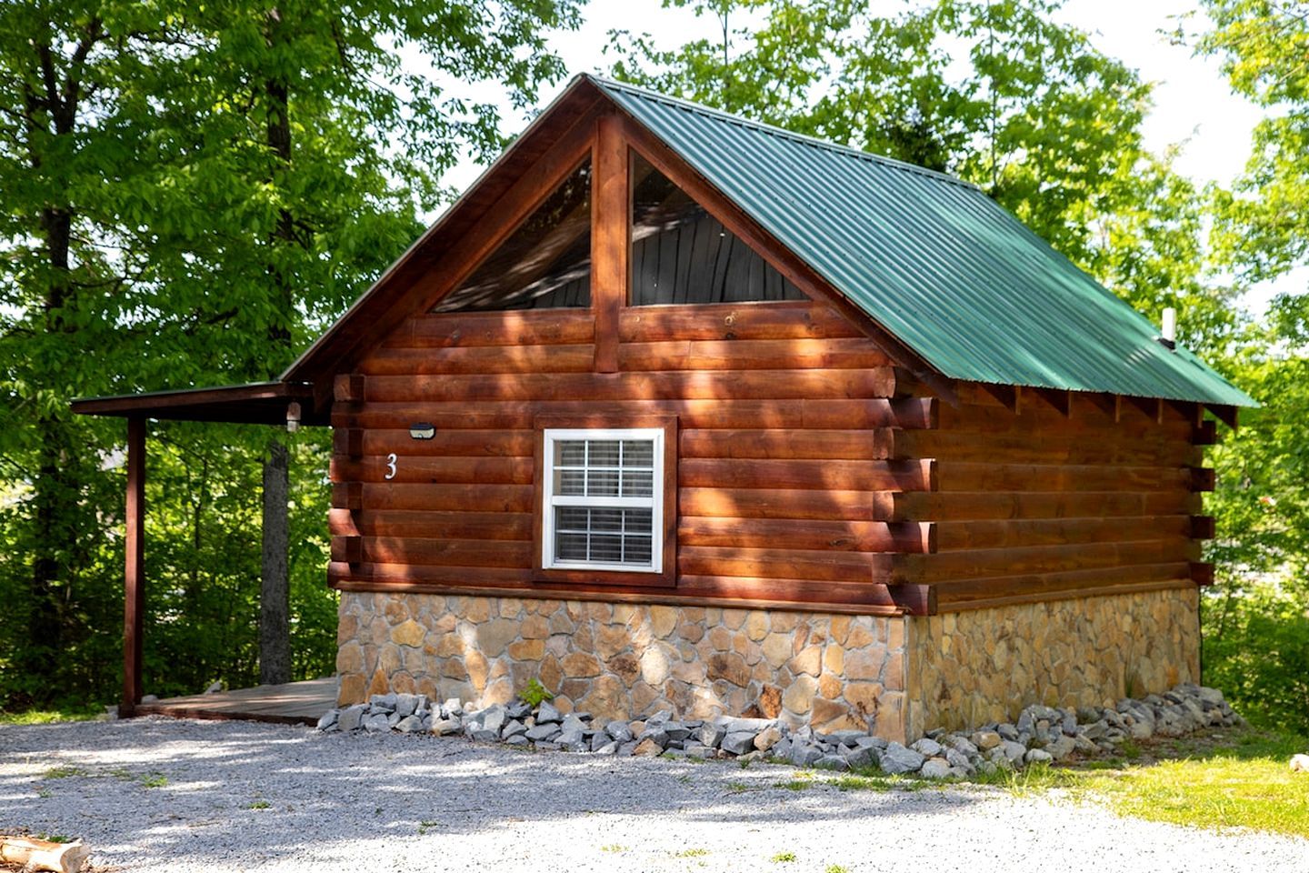 Eine Blockhütte mit Steinunterbau, Metalldach und einem Fenster.