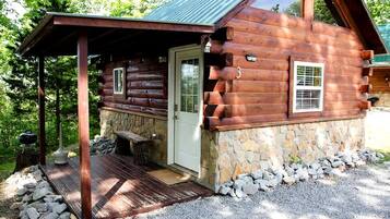 A log cabin with a porch, stone foundation, and a number '3' on the door.