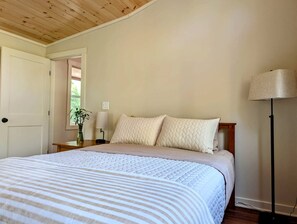 A bedroom with a bed, bedside tables, a lamp, and a door. - Peaceful Garden Retreat Near Acadia National Park, Maine (Ellsworth)