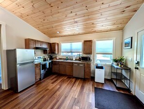 A modern kitchen with wooden flooring, stainless steel appliances, and a view through the window. - Peaceful Garden Retreat Near Acadia National Park, Maine (Ellsworth)