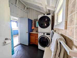 A compact laundry area with two stacked washing machines, a sink, and a towel rack. - Scenic Waterfront Summer Cottage with Ocean Views, Kayaking & Beach Access near Bar Harbor, Hancock Point, Maine (Hancock)