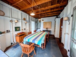 A dining area with a long table, wooden chairs, and a striped tablecloth. - Scenic Waterfront Summer Cottage with Ocean Views, Kayaking & Beach Access near Bar Harbor, Hancock Point, Maine (Hancock)