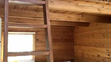A bunk bed with a ladder in a wooden cabin room.