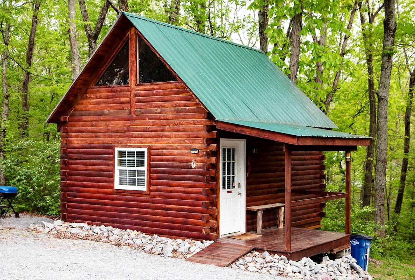 A wooden cabin with a green roof, a door, and a small porch.
