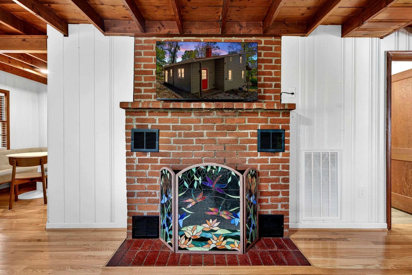 A fireplace with a stained glass design, a brick wall, and a wooden ceiling.
