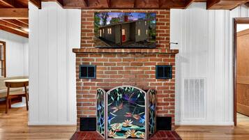 A fireplace with a stained glass design, a brick wall, and a wooden ceiling.