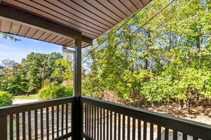 A covered outdoor area with a wooden railing, trees, and a clear sky.
