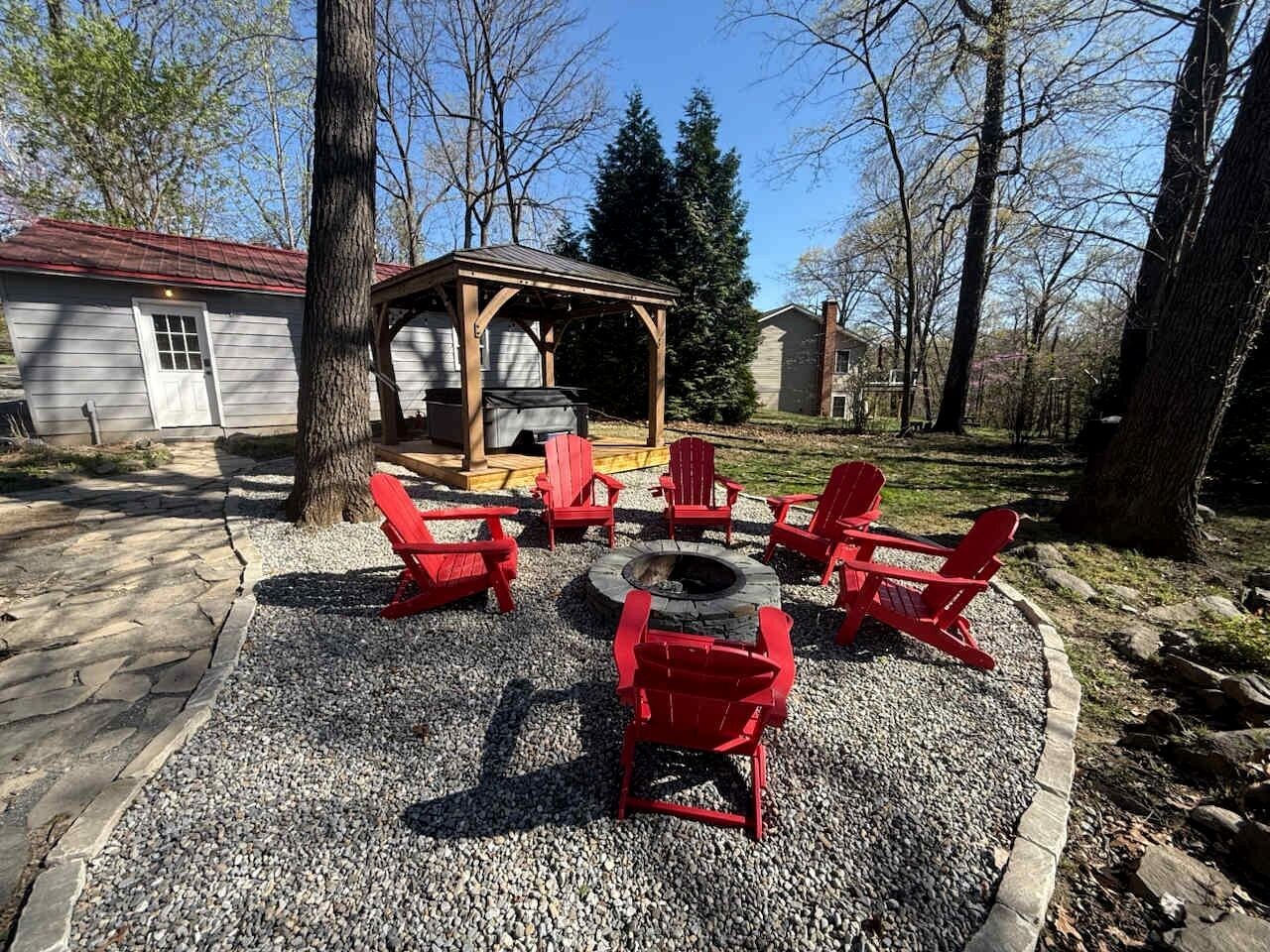 A covered outdoor seating area with red chairs and a fire pit.