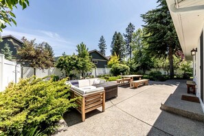 Eine Terrasse mit Gartenmöbeln, einer Holzbank und einem Tisch.