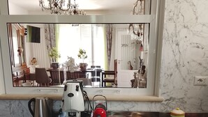 Una cocina con salpicadero de mármol, un refrigerador de acero inoxidable, una cafetera y una bandeja con tazas y bolsitas de té.