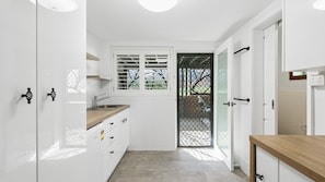 A compact kitchen with white cabinets, a wooden countertop, a sink, and a window with a view of the outside.