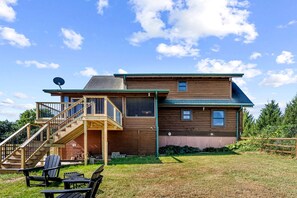 A two-story wooden house with a deck, outdoor seating, and a satellite dish. - Peaceful Mountain Cabin with Hot Tub, Screened Porch & Views Near Lost River, Baker WV (Baker)