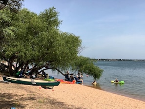 A beach with a row of boats, a tree, and people relaxing by the water. - Escape to a Scenic Lakeview Cabin Near Waterfalls, Vineyards & Starry Nights in Buchanan Dam, Texas (Buchanan Dam)